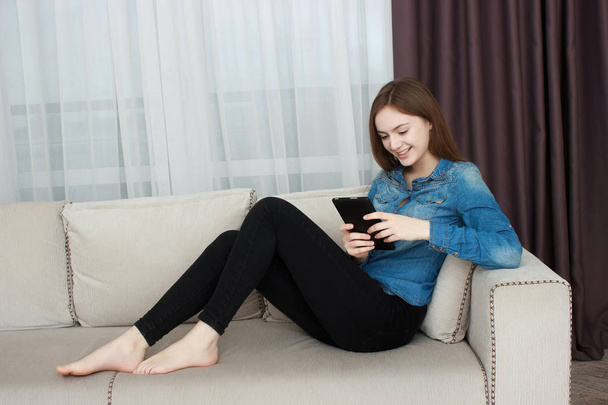 Woman relaxing on sofa while touching a tablet in a living room - Foto, immagini