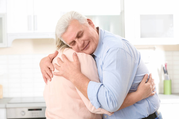 Mediana edad pareja abrazando en cocina
 - Foto, imagen