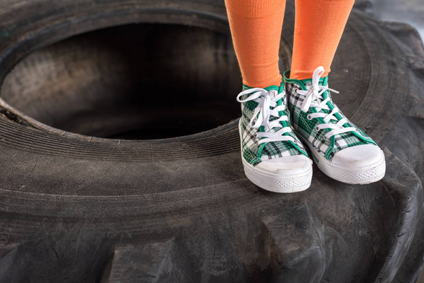 child in sportswear standing on tire - Photo, Image