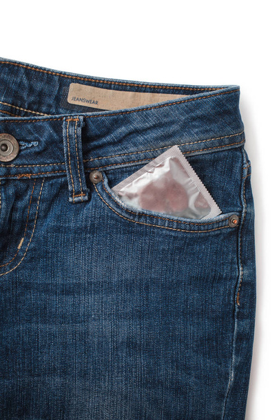 Condoms in package in jeans. Safe sex concept. Healthcare medicine, contraception and birth control. Close Up oral contraceptive pills. Protection against unwanted pregnancy. Protection against AIDS - Photo, Image