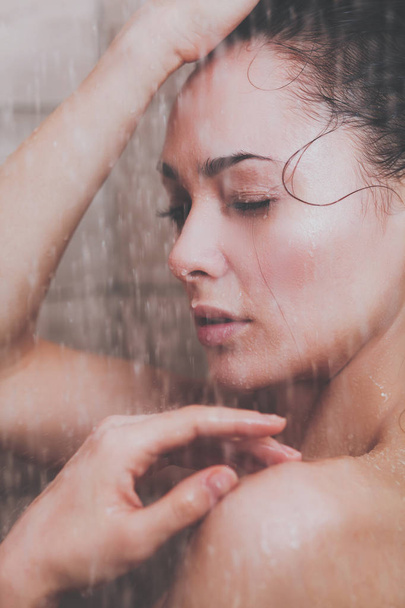 Young beautyful woman under shower in bathroom - Фото, изображение