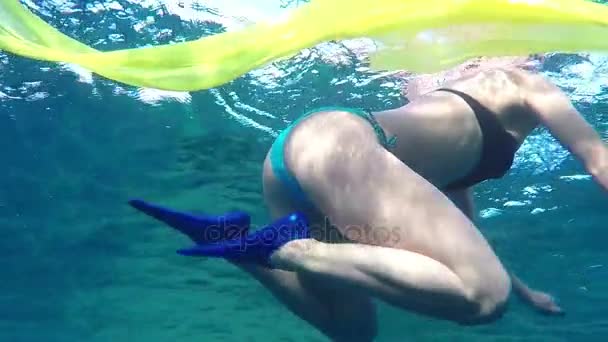 junge Frau wie eine Meerjungfrau hält ein gelbes Tuch in der Hand in blauem Wasser in slo-mo - Filmmaterial, Video