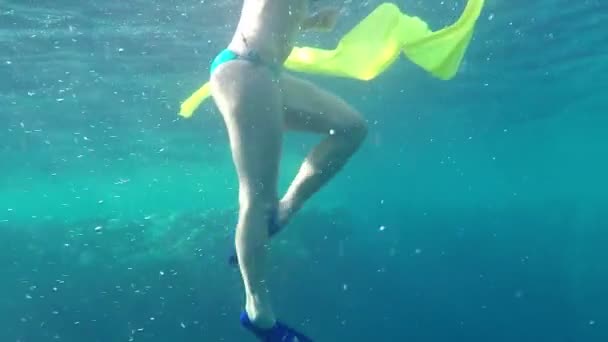 junge Schwimmerin hält ein gelbes Tuch in der Hand in hellen Gewässern im Slo-mo - Filmmaterial, Video