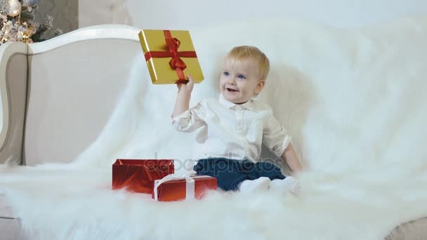 Cheerful child opens a Christmas gift and smiles - Imágenes, Vídeo