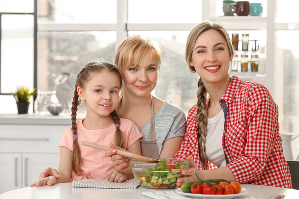 Young woman with mother and daughter in kitchen - Фото, изображение