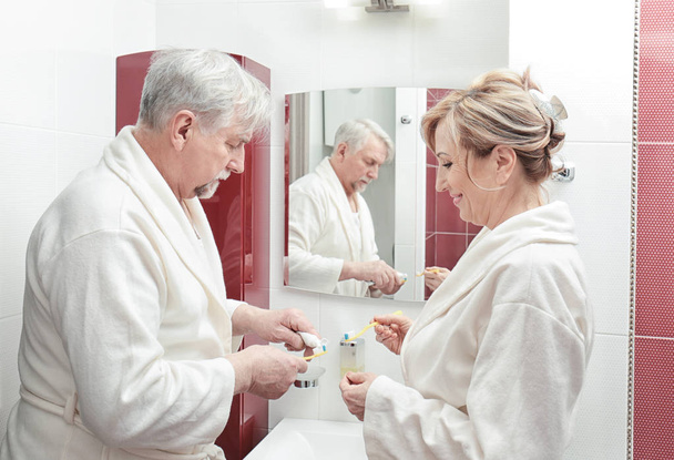 Elderly couple brushing teeth in bathroom - Fotoğraf, Görsel