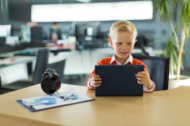 Netter Junge im Büro nutzt Tablet - Foto, Bild