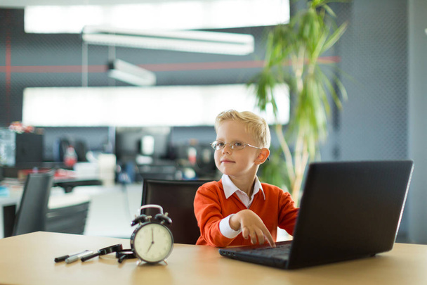 Χαριτωμένο αγόρι στο γραφείο να χρησιμοποιεί τον υπολογιστή - Φωτογραφία, εικόνα