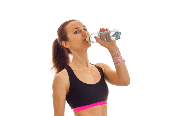 young slim girl in black top drinks water from a bottle - Φωτογραφία, εικόνα