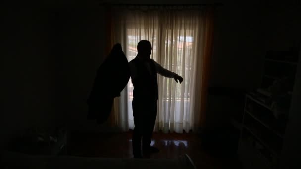 Silhueta de um homem no fundo de uma janela vestindo seu j
 - Filmagem, Vídeo