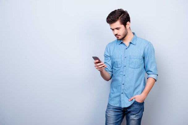 Vertical portrait of young guy in jeans shirt, typing sms and ho - Foto, immagini