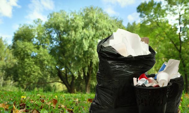 Cesta de basura negra completa y bolsas de plástico
 - Foto, imagen