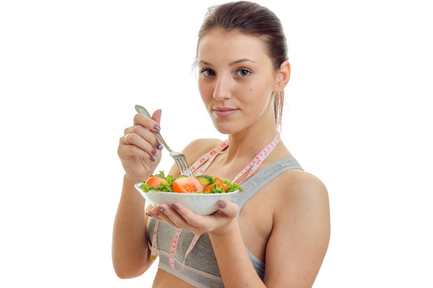 young beautiful girl looks straight and holding a plate of lettuce close-up - Photo, Image