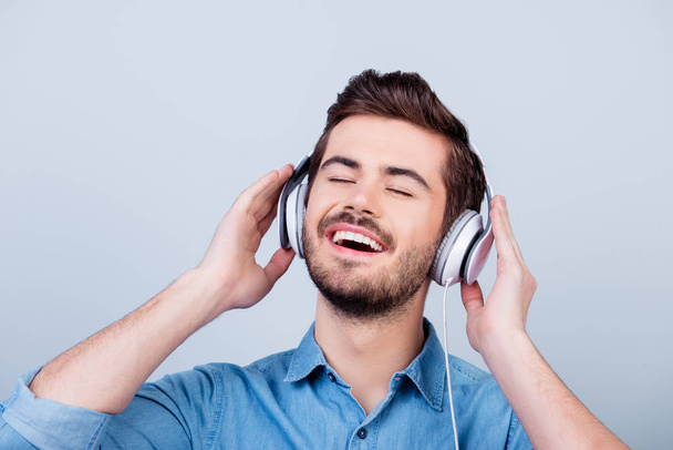 Close up portrait of cheerful young man enjoying listening to hi - 写真・画像