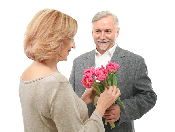 Senior man giving flowers to his wife on white background - Valokuva, kuva