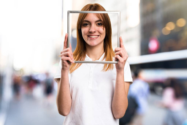 glücklich schönes junges Mädchen mit Rahmen auf unkonzentriertem Hintergrund - Foto, Bild
