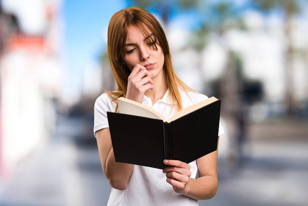 Beautiful young girl reading book on unfocused background - Foto, Imagem