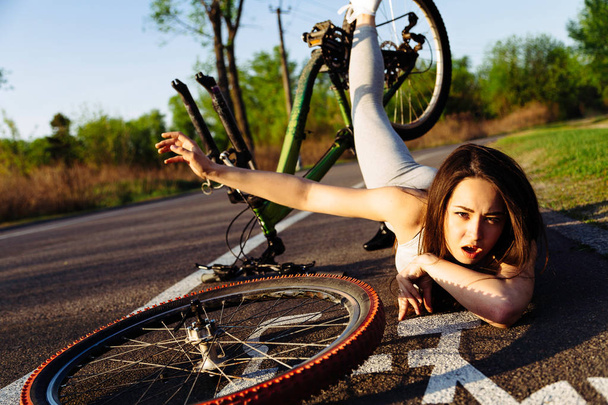 A rapariga caiu de bicicleta no parque. Acidente passeio de bicicleta perigoso no asfalto
. - Foto, Imagem
