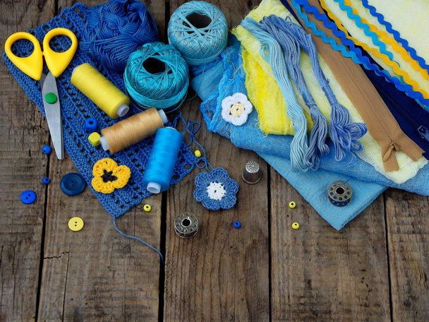 木製の背景に裁縫の黄色と青のアクセサリー。編み物、刺繍、縫製。中小企業です。趣味からの収入. - 写真・画像