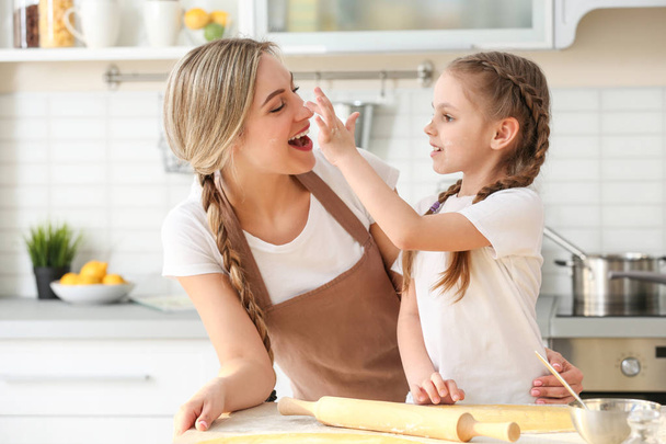 Young woman with her daughter cooking in kitchen - Foto, Bild
