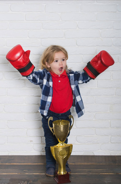 happy kid winner in boxing glove winning golden champion cup - Fotó, kép