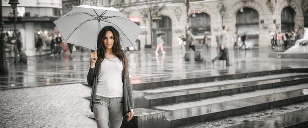 Donna con un ombrello sotto pioggia su una strada di città
 - Foto, immagini