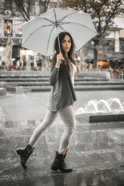 Woman with an umbrella under rain on a city street - Fotoğraf, Görsel