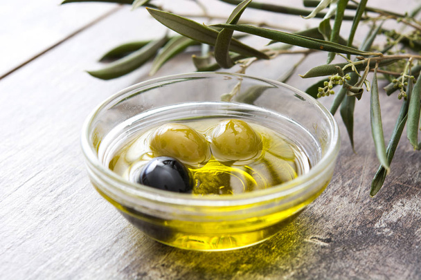 Virgin olive oil in a crystal bottle on wooden background - Photo, Image
