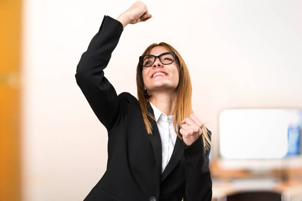 glückliche junge Geschäftsfrau im Büro vor unkonzentriertem Hintergrund - Foto, Bild