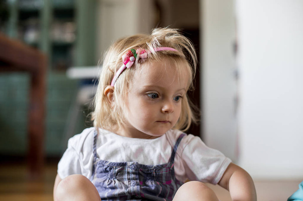 serious sad or thinking young baby caucasian blonde girl wearing headband portrait at home - Foto, imagen