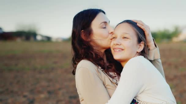 Mamá gentilmente abraza a su hija durante 11 años. Juntos miran en una dirección al sol poniente. Valores familiares
 - Imágenes, Vídeo