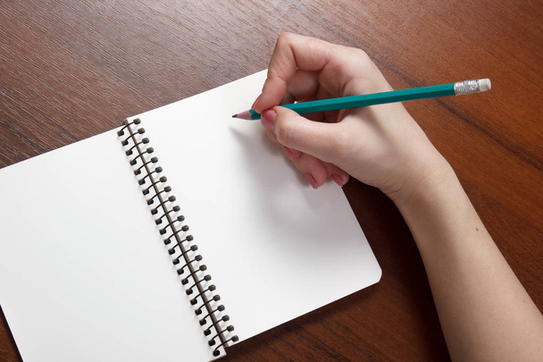 Closeup photo of girl writing in notebook with pencil - Foto, Bild
