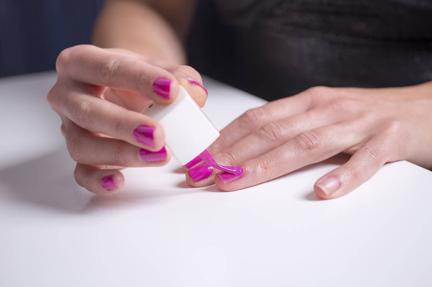 Girl paints her nails with pink nail polish - Photo, Image
