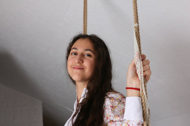 Portrait of young Hispanic woman in a nightgown on swing - Фото, изображение