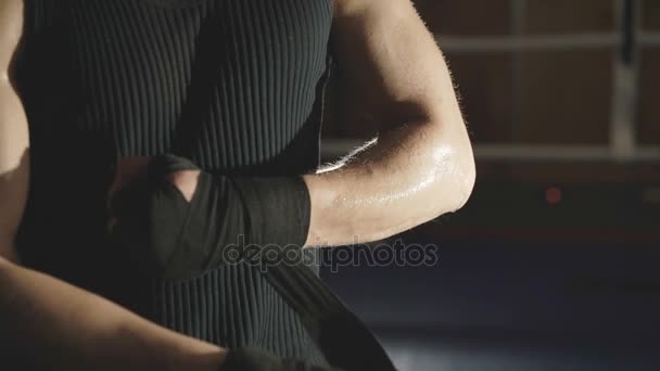 Male boxer wraps his hands with black bandage on the ring in the gym. Slowly - Materiał filmowy, wideo