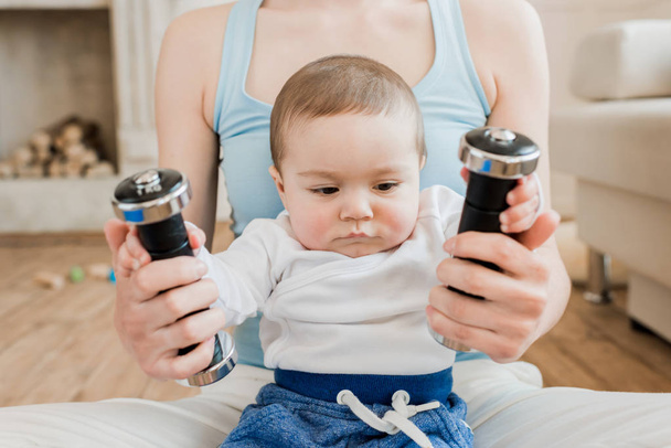 woman and baby boy playing with dumbbells - Foto, Bild