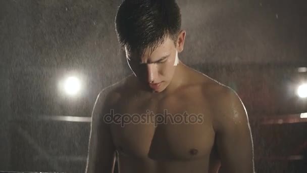 Portrait of boxer stands under water splashing on ring looking at camera. Slowly - Séquence, vidéo