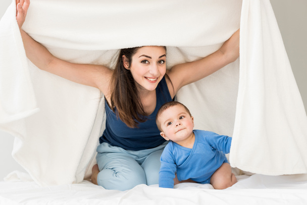 Мать с сыном играет под одеялом
  - Фото, изображение