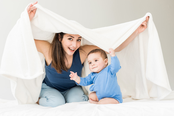 Mãe com seu filho brincando sob cobertor
  - Foto, Imagem