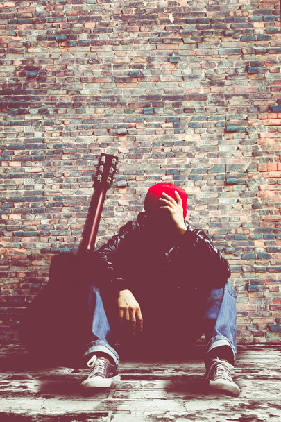 unhappy & worried asian musician thinking about his problem on brick wall background - Фото, зображення