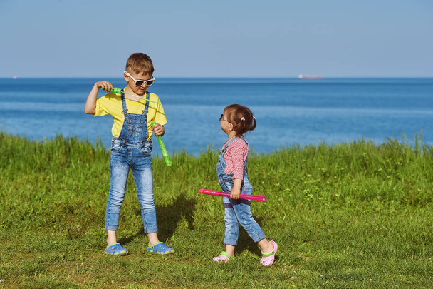 Les enfants en jeans jouent dans le fond de la mer. Le concept de la mode estivale pour enfants
 - Photo, image