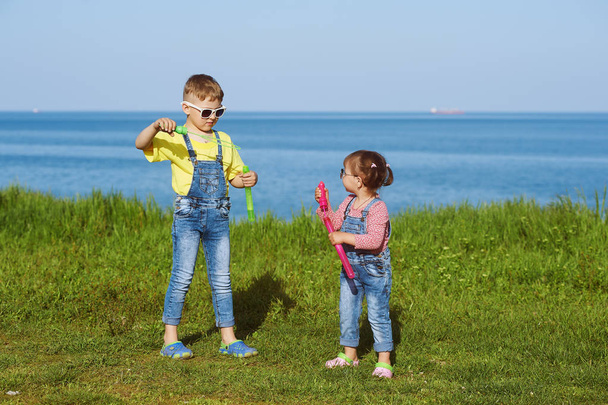 Les enfants en jeans jouent dans le fond de la mer. Le concept de la mode estivale pour enfants
 - Photo, image