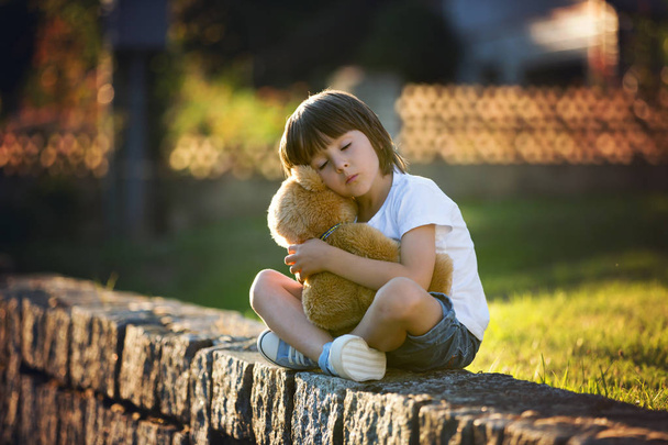Sweet boy, playing with teddy bear on a small rural path on suns - Φωτογραφία, εικόνα