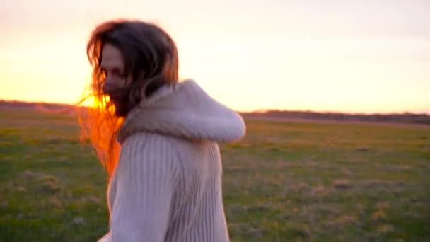 Vrouw loopt door een breed terrein bij zonsondergang, slow-motion - Video