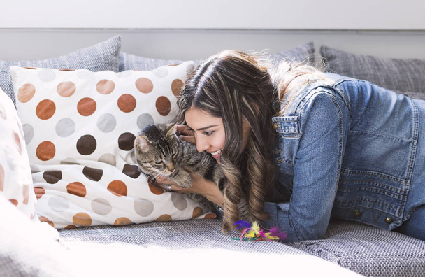 Woman on sofa playing with her cat in the living room - Photo, Image
