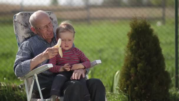 Abuelo dando plátano a su nieto al aire libre
. - Metraje, vídeo