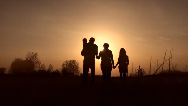 Silhouetten van grootouders met kinderen bij zonsondergang - Video
