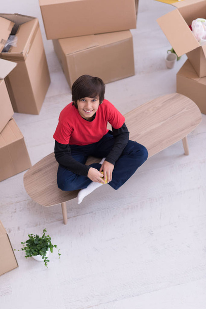 boy sitting on the table with cardboard boxes around him top vie - Φωτογραφία, εικόνα