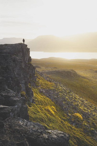 Wandelaar op een rotsachtige klif tijdens de zonsondergang. Geweldige sfeer met  - Foto, afbeelding