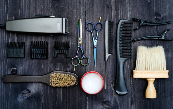 Hairdresser tools on wooden background. Top view on wooden table with scissors, comb, hairbrushes and hairclips, free space. Barbershop, manhood concept - 写真・画像